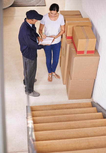 Unterschreiben Sie bitte hier Eine junge Frau erhält ein Paket von einem Lieferboten