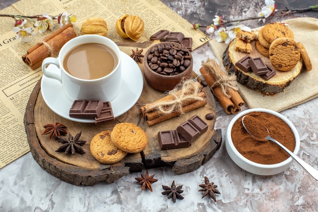 Untersicht Tasse Kaffeekekse Schüssel mit gerösteten Kaffeebohnen Schokolade Zimtstangen Anis Sterne auf Holzbrett Kakaoschale auf Tisch