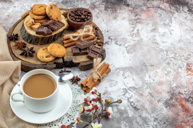 Untersicht Tasse Kaffeeschale mit gerösteten Kaffeebohnen und Kakao Schokolade Zimtstangen Kekse auf Holzbrett auf Tisch Freiraum