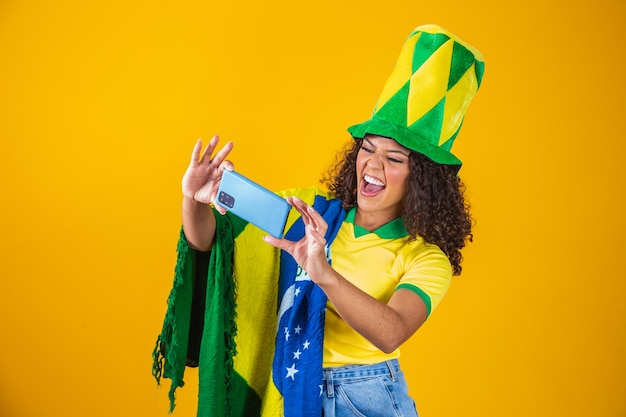 Unterstützer der brasilianischen Fußballmannschaft, der ein Tor feiert, indem er das Smartphone beobachtet