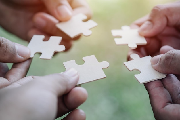 Foto unterstützung des teamwork-konzepts nahaufnahme der hände von vier geschäftsleuten, die weiße puzzleteile halten, puzzle zusammenbauen, gemeinsamen weg zur problemlösung finden, ausweg aus einer schwierigen situation finden