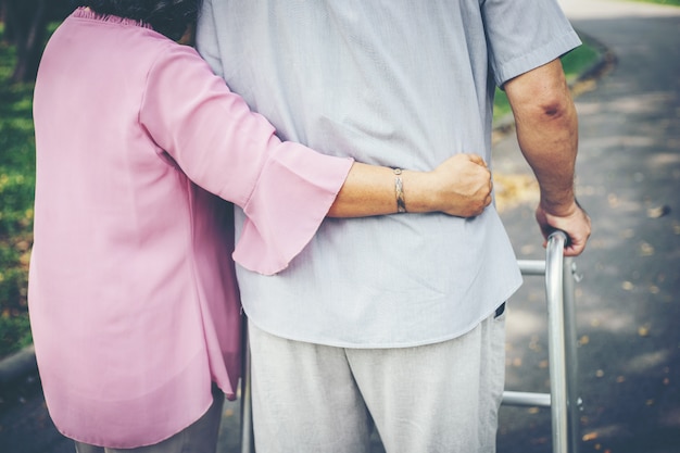 Unterstützung ihres älteren Patienten, der einen Rollator zur Unterstützung benutzt