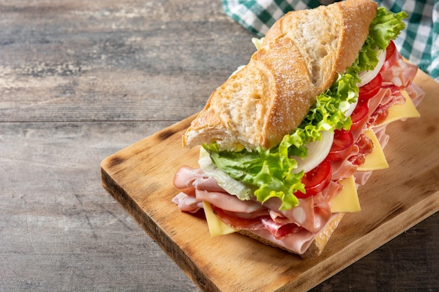 Unterwasser-Sandwich mit Schinken, Käse, Salat, Tomaten, Mortadella und Würstchen auf einem Holztisch