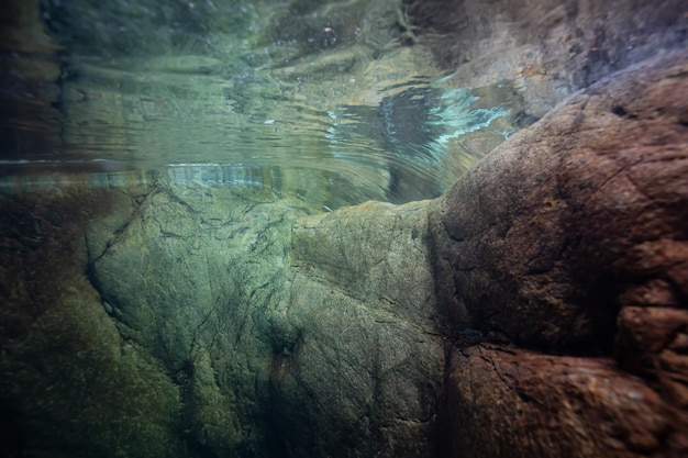 Unterwasserbild des Flusses in der felsigen Schlucht über einem Wasserfall