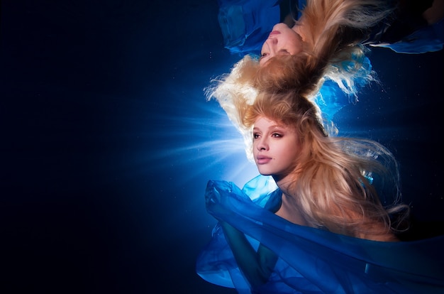 Unterwasserfoto hübsches junges Mädchen mit blonden langen Haaren in blauem Stoff