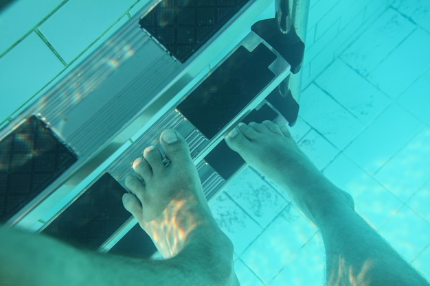 Unterwasserfoto, männerfüße treten auf die pooltreppe.