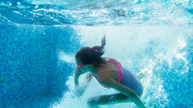 Unterwassernahaufnahmebild eines 10 Jahre alten Mädchens, das im Swimmingpool schwimmt und taucht