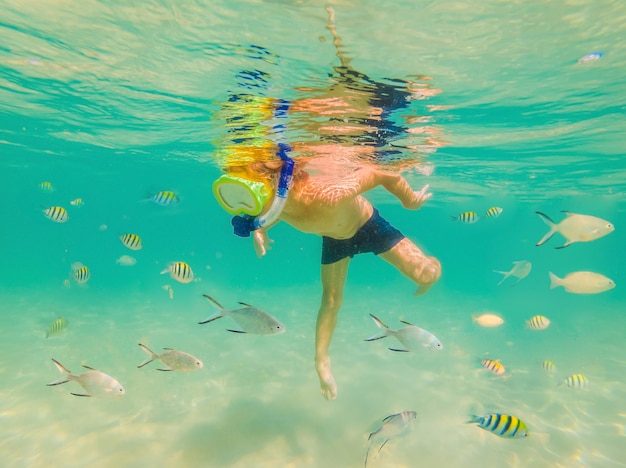 Unterwassernaturstudienjunge, der im klaren blauen Meer schnorchelt