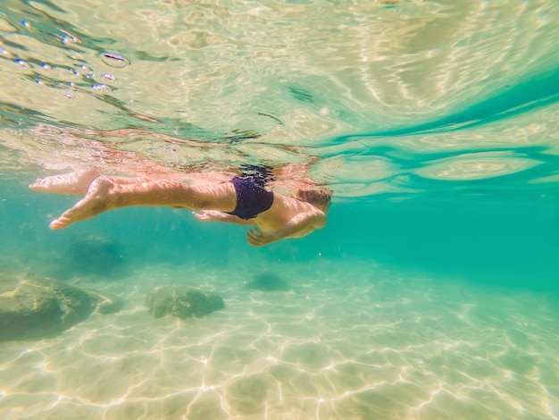 Unterwassernaturstudienjunge, der im klaren blauen Meer schnorchelt