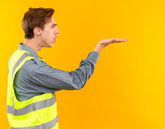 Unzufrieden in der Profilansicht stehen junger Baumeister in Uniform, der die Hand an der Seite ausstreckt