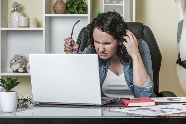 Unzufriedene Frau, die Daten vom Laptop liest