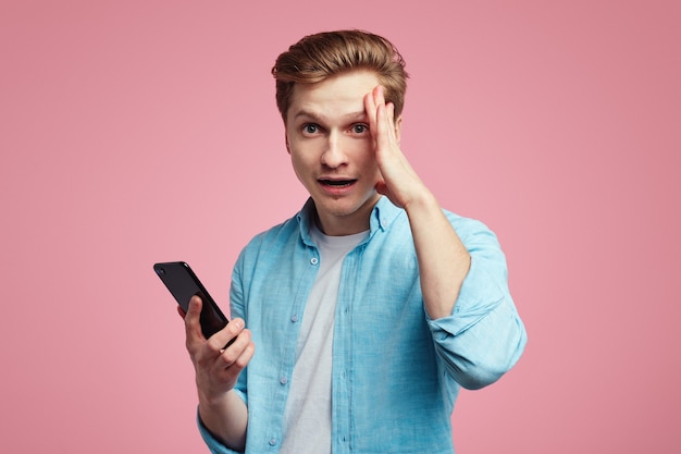 Unzufriedener junger unglücklicher Mann hat eine unangenehme Nachricht vom Smartphone