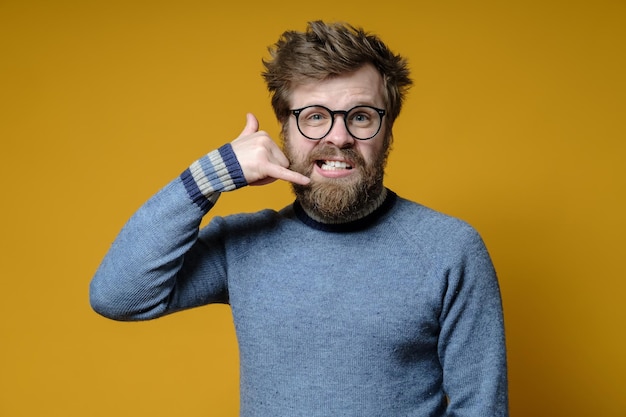 Unzufriedener nervöser Hipster macht mit seinen Fingern eine Telefongeste