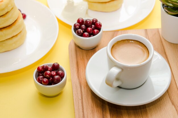 Foto Сup del café y de las bayas en fondo amarillo. syrniki. comida rusa. copia espacio