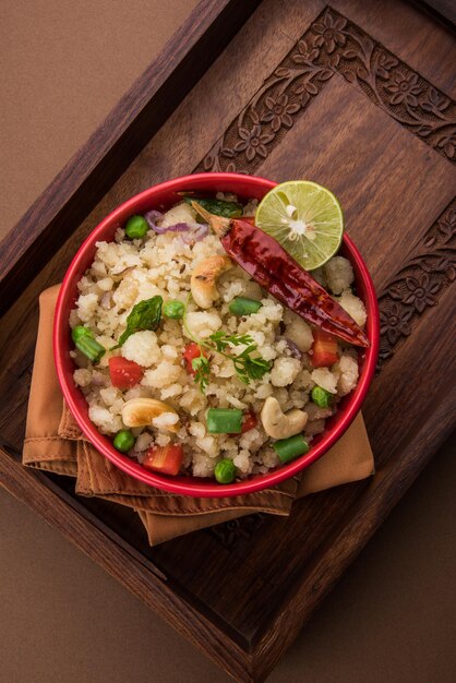 Upma ou uppittu é um prato de café da manhã popular no sul da índia e maharashtra. sêmola ou rava ou farinha de arroz grosso são os ingredientes principais. servido em uma tigela sobre fundo colorido ou de madeira