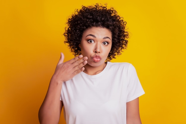 Ups schöne Frau überraschte Gesicht Palm Lippen Blick Kamera auf gelber Wand