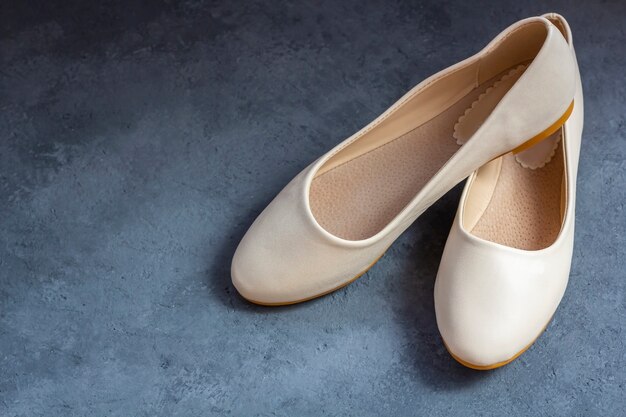 Urban damenschuhe: beige flats, slipper. lässige sommerschuhe auf dunklem hintergrund. frauen- oder jugendmode.