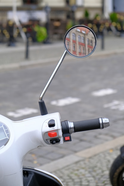 Urbana scooter branca está estacionada na estrada de paralelepípedos em um centro turístico da cidade