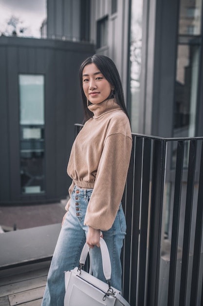 Urbane Mode. Trendy asiatische junge Frau, die draußen steht und gut aussieht