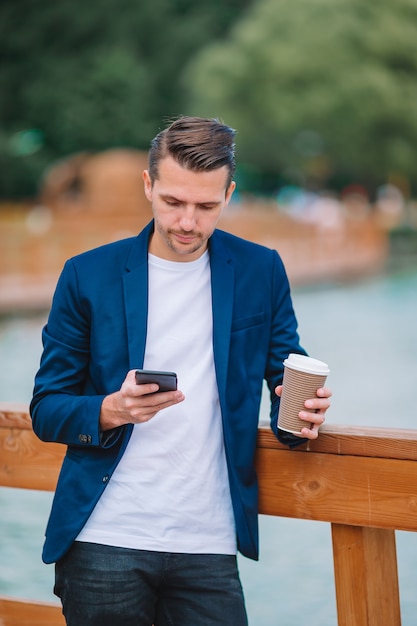 Urbano jovem feliz trabalhando e tomando café na cidade europeia ao ar livre