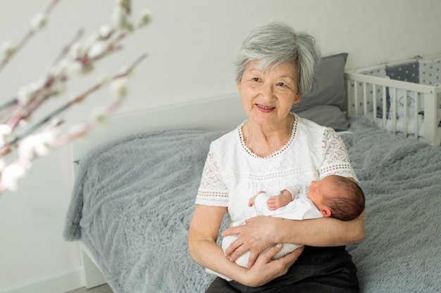 Urgroßmutter hält eine neugeborene Urenkelin in den Armen