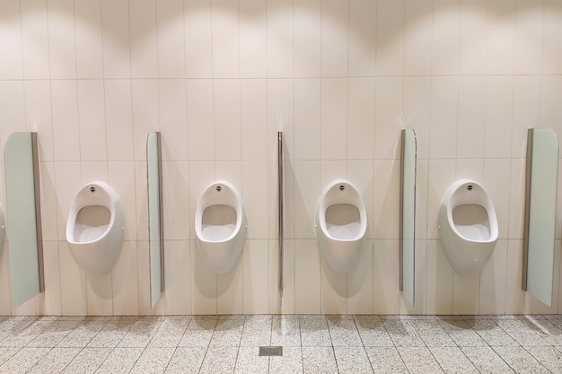 Urinarios blancos en la sala de hombres en la vista frontal de la pared