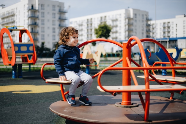 Urkomischer kleiner Junge auf einem leeren Spielplatz während der Quarantäne ohne Schutz