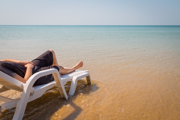 Urlaub am tropischen Strand Woman&#39;s Beine am Strand Bett mit klarem Meerwasser Hintergrund