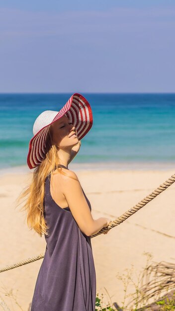 Urlaub auf der tropischen Insel Frau mit Hut, die Meerblick von der Holzbrücke im Hochformat genießt