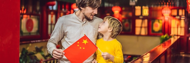 Urlaub in China genießen glückliche Touristen Vater und Sohn mit einer chinesischen Flagge auf chinesischem Hintergrund