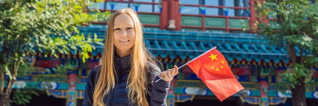 Urlaub in China genießen junge Frau mit nationaler chinesischer Flagge auf dem Hintergrund des Alten