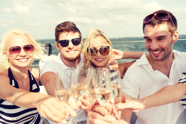 Foto urlaub, reise, meer, freundschaft und personenkonzept - lächelnde freunde mit gläsern champagner auf yacht