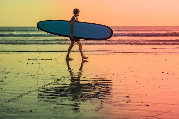 Urlaub Silhouette eines Surfers mit seinem Surfbrett nach Hause bei Sonnenuntergang mit Textfreiraum.