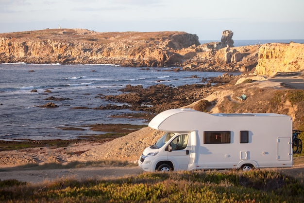 Urlaub und Reise in Wohnwagen. Wohnmobil Wohnmobil auf Küstenstraße mit Sonnenuntergang