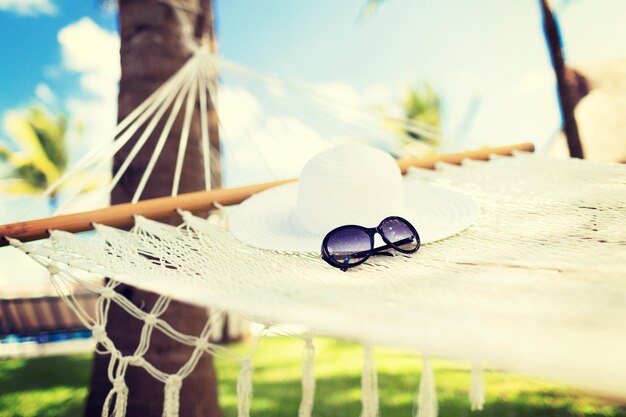 Urlaubs- und Urlaubskonzept - Bild einer Hängematte mit weißem Hut und Sonnenbrille