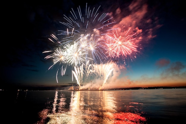 Urlaubsfeuerwerk über Wasser mit Reflexion auf dem schwarzen Himmelshintergrund