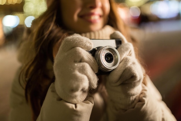 Foto urlaubsfotografie und menschen konzept nahaufnahme von glücklicher junger frau mit kamera auf dem weihnachtsmarkt am winterabend