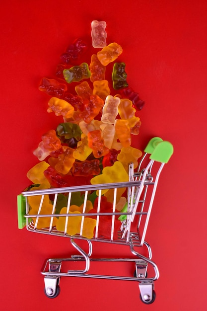Ursinhos de goma em uma pequena cesta de supermercado em um fundo vermelho.