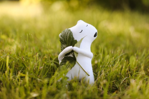 Urso de brinquedo artesanal bonito ecologicamente correto na grama no dia ensolarado de verão