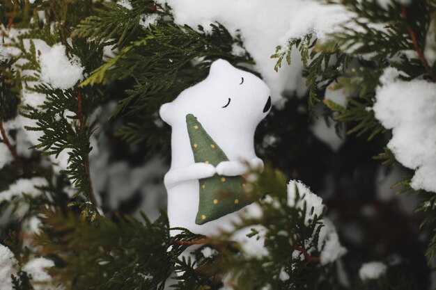 Urso de brinquedo branco polar em um galho de árvore de Natal Feliz Natal e Feliz Ano Novo