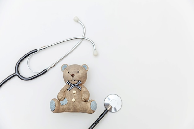 Urso de brinquedo de design minimalista e estetoscópio de equipamentos de medicina isolado no branco