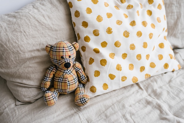 Urso de brinquedo macio ao lado dos travesseiros na cama