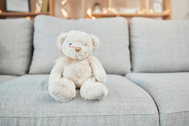 Urso de pelúcia brinquedo infantil e brinquedos de bebê em um sofá da sala de estar para um presente de natal ou aniversário Peludo macio e crianças urso em um sofá de sala de estar sem pessoas e presente de feriado com luzes bokeh