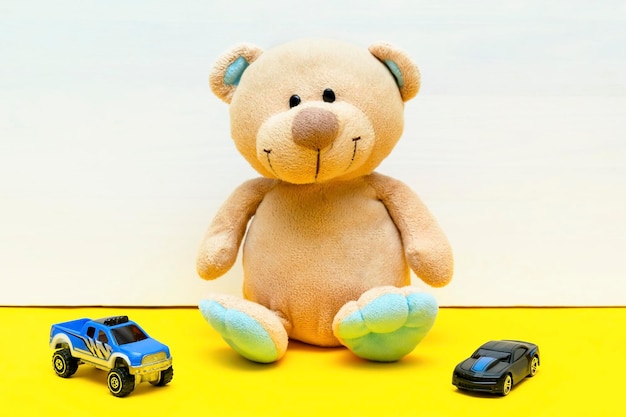 Urso de pelúcia com carros brinquedos para crianças brincam no desenvolvimento infantil do bebê de fundo amarelo branco Brinquedos educativos para o conceito de criança criança