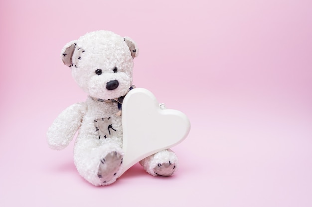 Urso de pelúcia com coração de amor no fundo rosa, cópia espaço