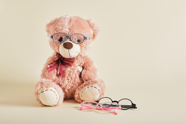 Urso de pelúcia com óculos no fundo bege