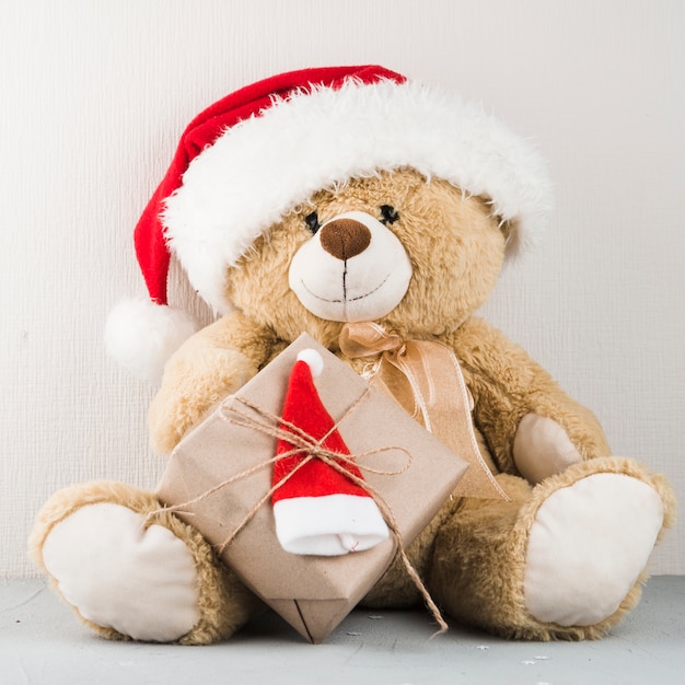 Urso de pelúcia no chapéu de papai noel com presente