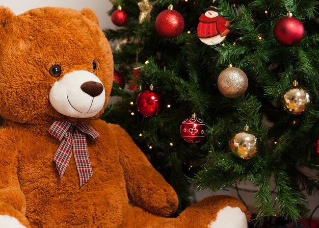 Urso de pelúcia perto de árvore de Natal com presentes