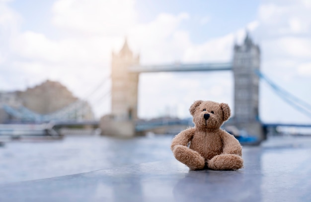 Urso de pelúcia sentado sozinho com o fundo desfocado de ponte de torre de Londres