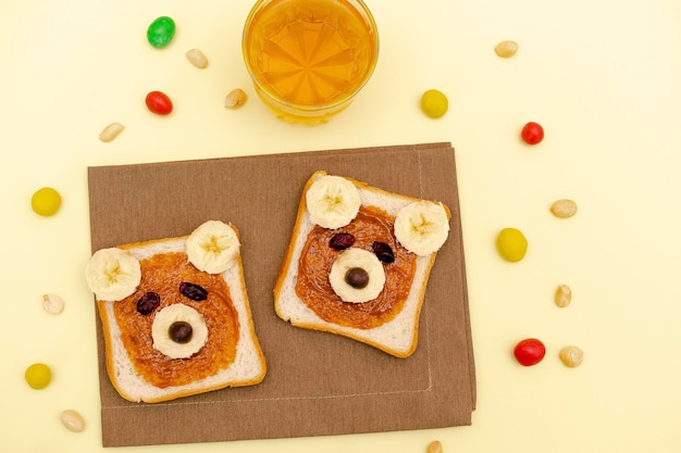 Urso fofo engraçado enfrenta sanduíche de pão torrado com manteiga de amendoim banananutsjuice Crianças para crianças sobremesa doce café da manhã saudável almoço arte comida na placa Close close uptop view